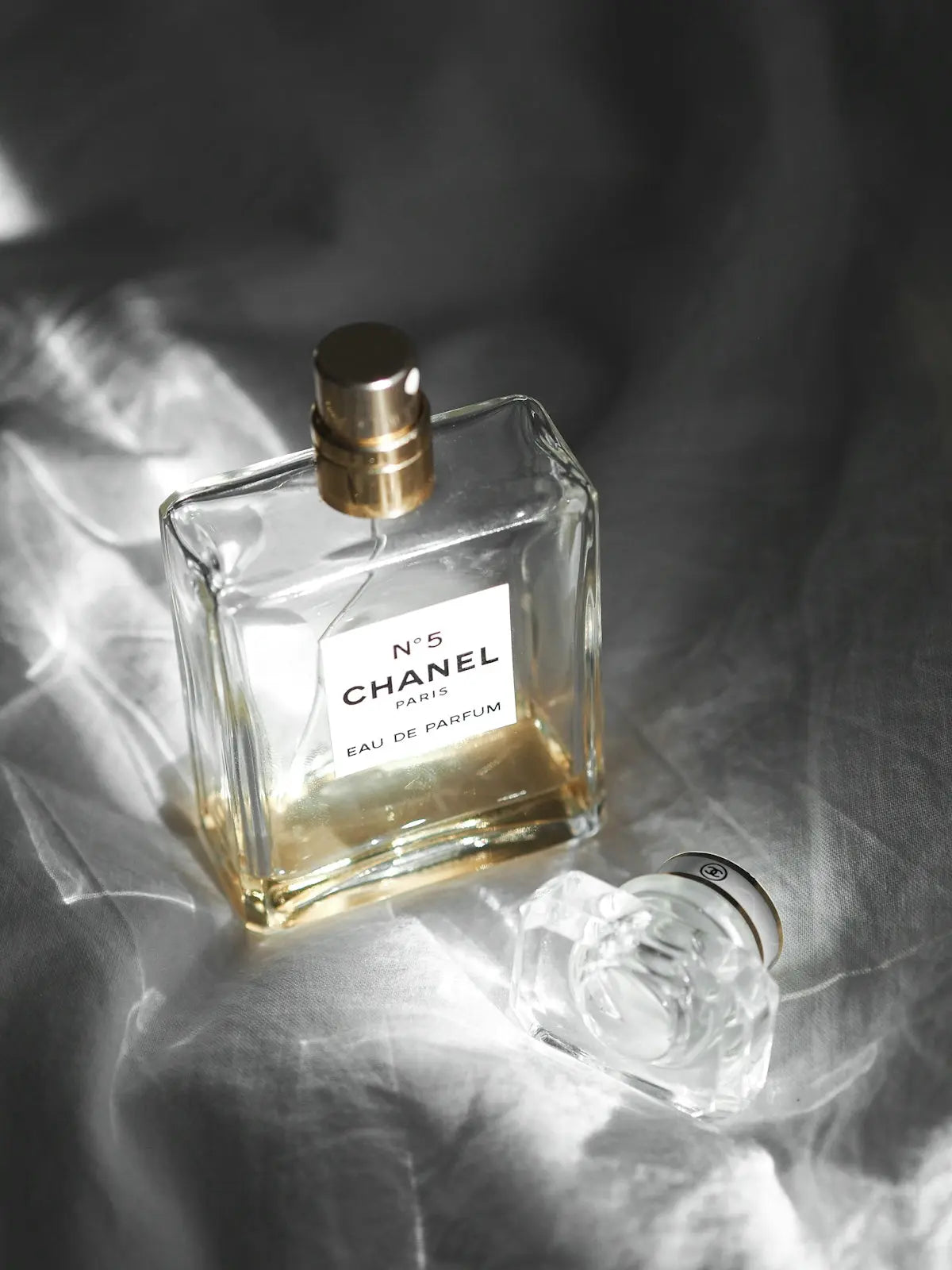 clear glass perfume bottle on white textile